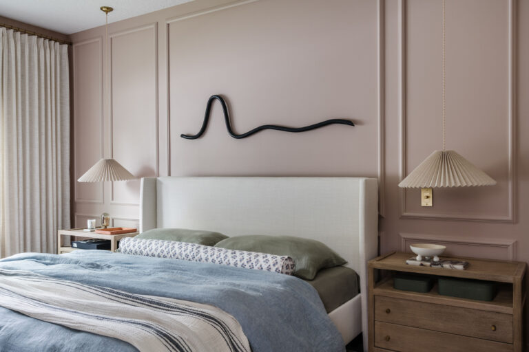 Primary bedroom with pink walls, picture molding, pleated hanging pendants and squiggle wall art.